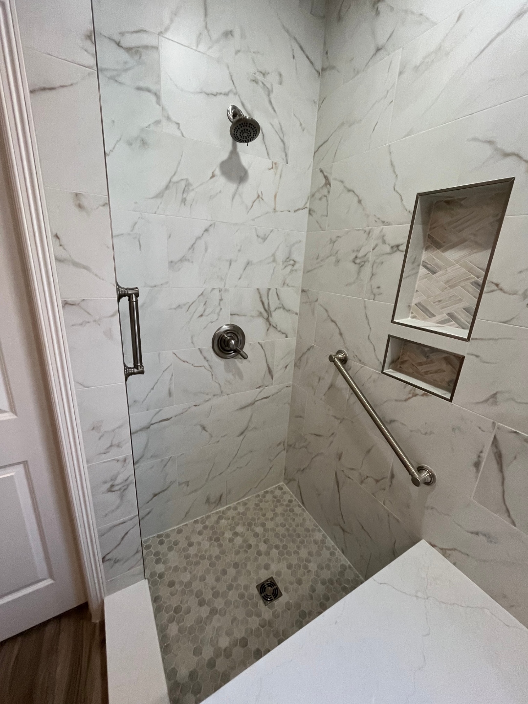 Marble tile walk-in shower installation with grab bars by Haltex Plumbing